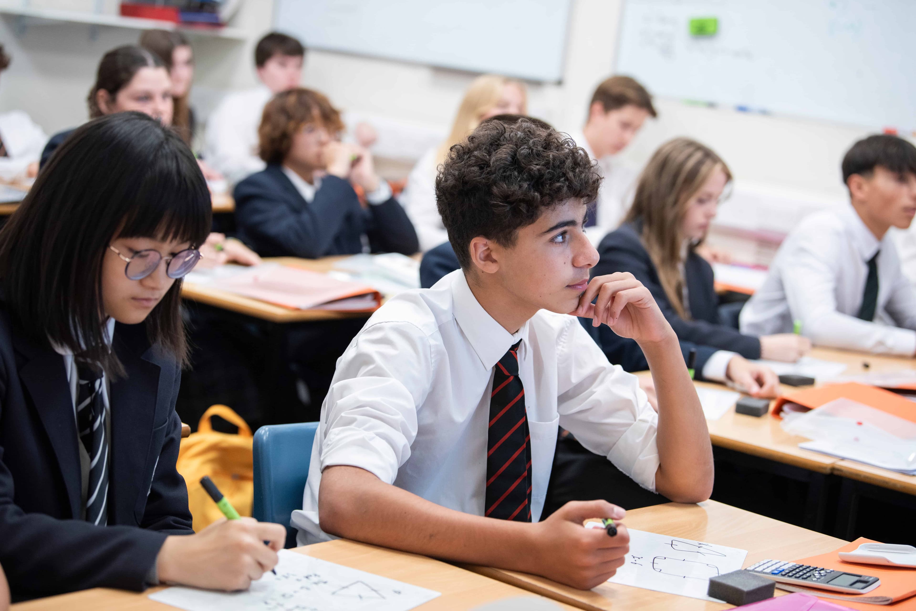 A classroom setting with pupils making notes and listening intently
